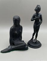 Photo showing both small metal statues: seated mermaid and standing classical nude woman with foundry tag.
