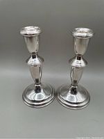 Pair of matching polished sterling silver candlesticks with rounded weighted bases and classic tapered shape.