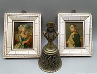 Framed prints of Josephine and Napoleon Bonaparte with brass Battle of Waterloo bell between them.