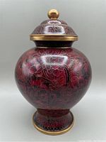 Front view of the maroon cloisonné ginger jar with lid on, showing floral patterns and round body shape with gold-tone details.