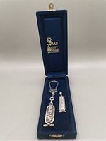 Full view of the blue velvet presentation box with key chain and pendant displayed inside.