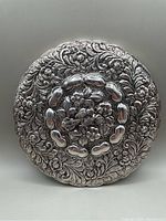 Front side of silver frame showing embossed floral repousse decoration and central bead ring