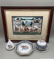 Full view of three blue elephant Wedgwood porcelain items with framed Indian painting in background.