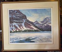 Framed oil painting showing a river with snowy mountains and trees, full front view.