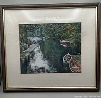 Framed pastel painting showing view of waterway, boats and foliage with artist signature visible.