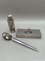Photo showing all three items: rectangular stamp box with pyrite cluster lid, metal letter opener with pyrite handle, cylindrical match holder with pyrite top.