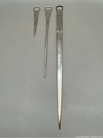 Photo showing all three silver plated meat skewers of varying lengths and shapes laid side by side on a flat surface.