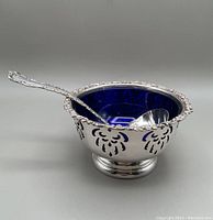 Silver plate bowl with cobalt blue glass liner and ladle inside bowl shown from angled side