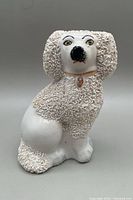 Front view of antique Victorian Staffordshire pottery poodle figurine showing textured fur and painted facial features.