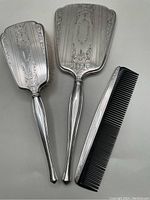 Photo showing whole sterling dresser set: hairbrush, hand mirror, and comb arranged on flat surface.
