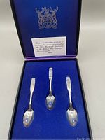 Three sterling silver commemorative spoons displayed in original blue box.
