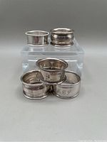 Five sterling silver napkin rings displayed showing variety and sizes.