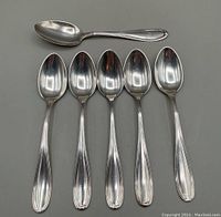 All six sterling silver teaspoons arranged with the monogrammed spoon on top and five matching spoons below showing front view.