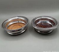 Two silver plate wine bottle coasters side by side, front view