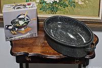 Photo showing the boxed 9 1/4" steel mini wok set with wooden handle and aluminum lid, next to the vintage enameled steel roasting turkey dish on wooden table.
