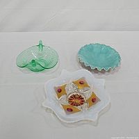 Top view of all three decorative dishes: green pressed glass bird nest dish with two birds, ceramic turquoise ruffled dish, and vintage Goofus glass candy dish