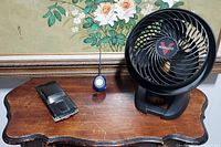 Vornado fan, Philco car-shaped radio, and People Soft portable radio on wooden table with floral wallpaper background.