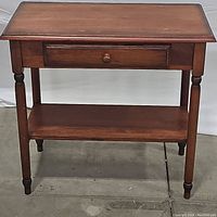 Wooden foyer table, front view showing drawer and shelf, turned legs.