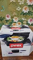 Box showing Pyrex portable dish set with dishes, lids, and bag