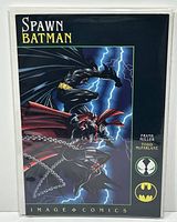 Front cover of Spawn Batman #1 comic book featuring artwork of Batman and Spawn in action poses with storm and lightning background. Comic is in protective bag and board.