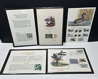 Four framed folios displaying US duck stamps and First Day Cover presentation cards with ducks' artwork and historical text.