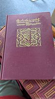 Front cover of the hardcover book showing burgundy cloth binding with gold embossed title 'Rubaiyat Omar Khayyam' and ornate decorative emblem.