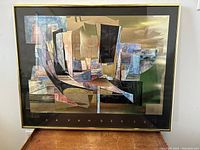 Framed abstract boat harbour art poster by Isa van der Zee, showing boats in geometric style, tilted slightly and resting on a wooden surface.