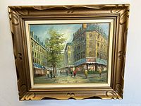 Full view of the framed oil painting showing a Paris street scene with architecture, trees, and pedestrians.