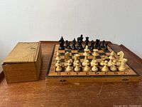 Front view of the chess set on wooden foldable board with the storage box adjacent.