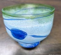 Side angle of the signed blue and green glass bowl showing blue leaf design and clear textured glass
