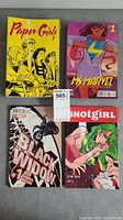 Photo showing four comic books: Paper Girls #1 with yellow cover, Ms. Marvel #1 with pinkish background, Black Widow #1 with shattered glass effect and motorcycle imagery, and Snotgirl F/W 2018 #2 featuring a green-haired woman.