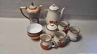 Full group showing two tea pots, four cups, sugar container, creamer, and four small white bowls