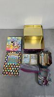 Photo showing Pokemon cards, Deluxe Essential Handbook, metal lunchbox, and painting framed.