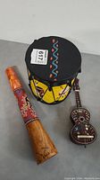Photo showing all three instruments: the drum, the horn, and the toy guitar, displaying size and decorative details