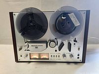 Front three-quarter view showing dual reel spindles with reels loaded, control panel and wood-grain side panel