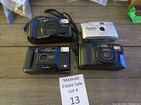 Overview of four assorted film cameras arranged in two rows on wooden tabletop