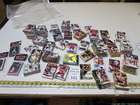Full assortment of hockey cards and three unopened basketball card packs spread on a table with measuring tape for scale.