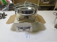 4 quart stainless steel Casa Bela chafing dish on top of its original box labeled with lot number