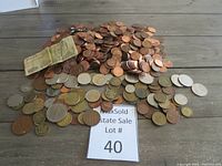 Overview of collection showing a large pile of copper pennies, assorted foreign coins of various sizes and colors, and an older currency note.