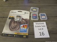 Four memory cards visible on the table, three removed from packaging in clear plastic cases, PNY card in original packaging next to them