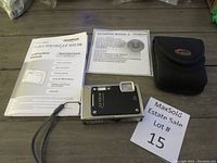 Olympus Stylus 1030 SW camera, instruction manual, software CD and padded soft case laid out on table