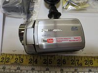 Close-up of Panasonic SDR-S15 camcorder side with model label and zoom control visible along with YouTube logo sticker indicating compatibility or promotion