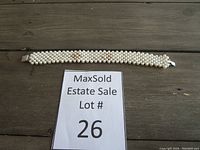 Showing the full length of the multi-row white pearl bracelet laid flat on a wooden surface with lot number visible.