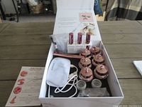 Open box showing the content of the Sistaco nail kit including liquids, powder jars, LED lamp, USB cable, and brush