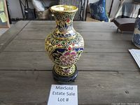 Full view of metal decorative vase with colored inlay on wooden stand, showing shape and overall design