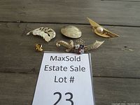 Overview of six vintage brooches including feather, bee, sword, oval design, and gold-tone brooch with faux pearl.