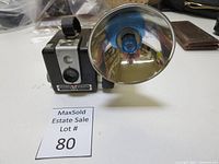 Front angle view of Brownie Hawkeye Camera with Flash attachment and MaxSold lot number marker.