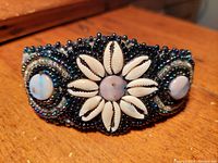 Close-up front view of the handcrafted bracelet showing the shell daisy centerpiece and surrounding beadwork.