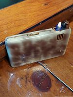 Vintage makeup compact closed with working lighter lit, showing marbled exterior.