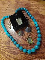 Lot showing all items together: turquoise blue bead necklace, Tommy Hilfiger watch in box, round brass earrings, brass pendant necklace with Lord's Prayer.